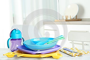 Set of plastic dishware on white marble table. Serving baby food