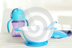 Set of plastic dishware on white table indoors. Serving baby food