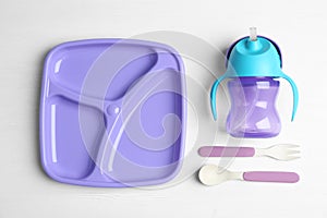 Set of plastic dishware on wooden table, flat lay. Serving baby food