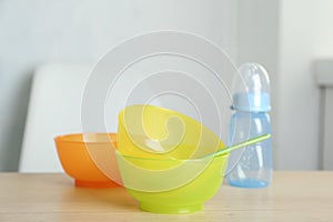 Set of plastic dishware on wooden table indoors. Serving baby food