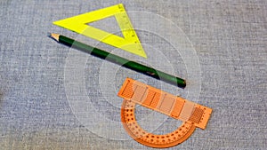 Set of plastic rulers and a protractor between the pencil