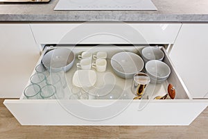 Set of plates, cups, knives, forks and wine glasses on the shelf in the kitchen cabinet