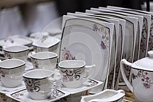 A set of plates and cups in white tone stands on a wooden table