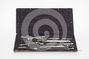 Set of precision technical drawing instruments in black case.