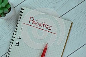 Set Priorities write on a book isolated on Wooden Table