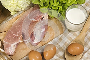 Set products consisting of bread, milk, pork, eggs , and vegetable on wooden table background