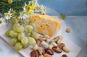 A set of products: grapes, different nuts on a wooden background, wooden old kitchen board