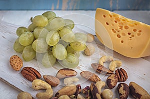 A set of products: grapes, different nuts on a wooden background, wooden old kitchen board