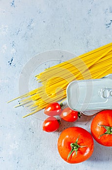 A set of products for the preparation of pasta, spaghetti, tomatoes, canned food tuna. Food donation on a blue background.