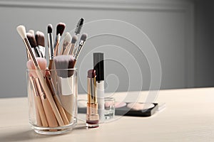 Set of professional brushes and makeup products on wooden table indoors, space for text