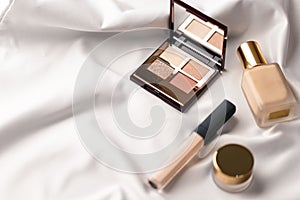 Set of professional elite decorative cosmetics for make-up on white silk cloth. Textile background. Copy space. Beauty and fashion