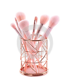 Set of professional makeup brushes in golden holder isolated