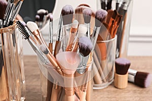 Set of professional makeup brushes and mirror on wooden table, closeup