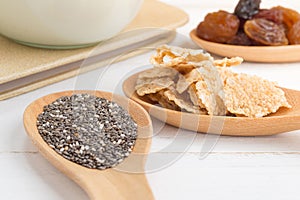 Set of raisins, whole wheat grain flakes and chia seeds in woode