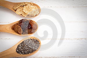 Set of raisins, whole wheat grain flakes and chia seeds in woode