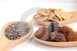 Set of raisins, whole wheat grain flakes and chia seeds in woode