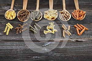 A set of raw pastas on spoons on a wooden table