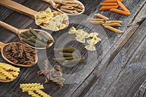 A set of raw pastas on spoons on a wooden table