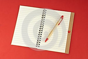 Set of recycle paper notebook and pen. Open diary notebook on red background