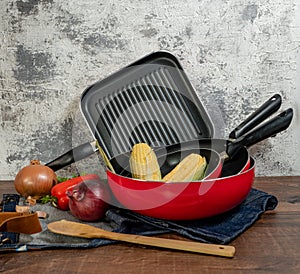 a set of red pans with vegetables on a wooden table