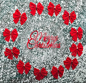 Set of red ribbon bows arranged in the shape of a circle on background with snowflakes