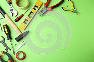 Set of repair tools on green background, flat lay. Space for text