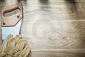 Set of safety gloves stainless handsaw on wood board constructio