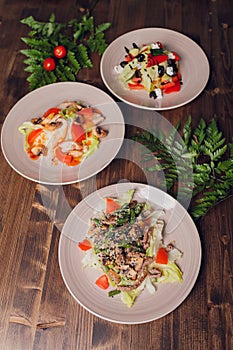 Set of salads on a dark background. Greek salad, Caesar salad, vegetable salad.