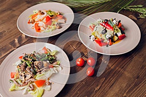 Set of salads on a dark background. Greek salad, Caesar salad, vegetable salad.