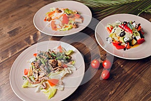 Set of salads on a dark background. Greek salad, Caesar salad, vegetable salad.