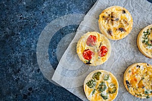Set of savory mini tarts on a baking paper. Vegetable quiches wi