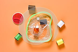 Set of scattered sewing accessories near transparent plastic handbag on orange tailors desk in workshop