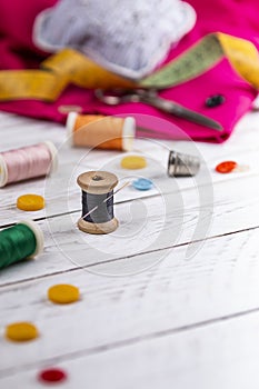 Set of scattered sewing accessories on white wooden table