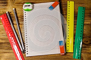 Set of school stationery supplies. Blank notepad, rulers, pencils, erasers and sharpener on wooden desk. Top view