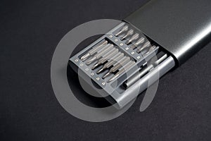 A set of screwdrivers with bits in a case on a dark background. Close up, for work