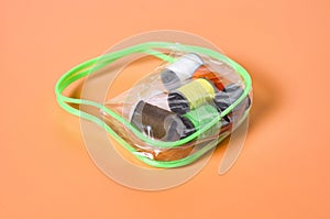 Set of sewing accessories in transparent plastic handbag lies on orange tailors desk in workshop