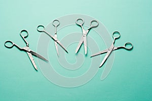 Set of sharp steel scissors on the turquoise surface. Open scissors on the table. Beauty Scope. Top view. Flatly.