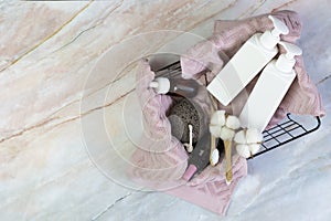 Set of shower accessories in a basket on a marble background. contains bottles of cosmetics, loofah, toothbrushes, towel. DIY eco