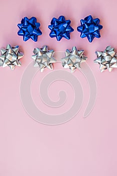 Set of silver and blue bows on blue. Holiday`s ribbon bows for decoration gifts.Silver ribbon with bow tie on blue paper