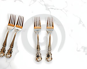 A set of silver cocktail forks displayed on a marble table surface