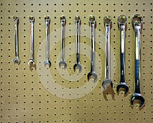 A set of silver metal wrench hand tools in a row hanging