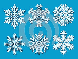 Set of six white paper cut out vector snowflakes on blue background.