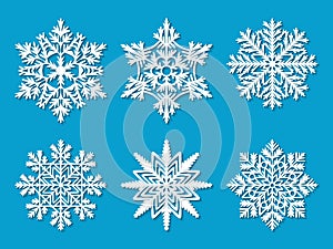 Set of six white paper cut out vector snowflakes on blue background.