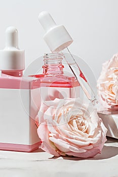 Set of skin care cosmetic products in dropper bottles decorated with rose flowers. Unbranded labels for your design