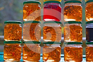 A set of small jars of different colors with jam without labels.