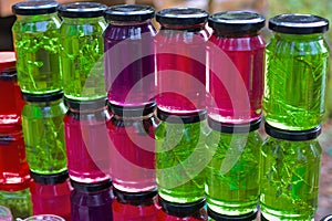 A set of small jars of different colors with jam without labels.