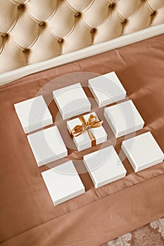 Set of small minimalist gift boxes for jewelry spread out on luxury bed.