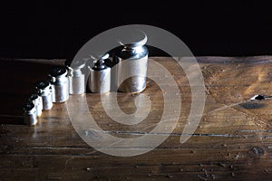 Set of small weights for jewelry scales on a wooden table. front and background blurred with bokeh effect