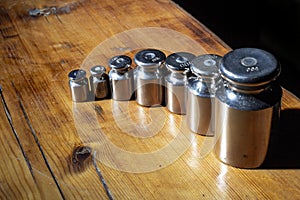 Set of small weights for jewelry scales on a wooden table. front and background blurred with bokeh effect