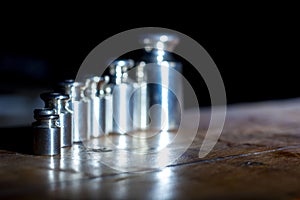 Set of small weights for jewelry scales on a wooden table. front and background blurred with bokeh effect